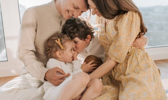 A happy family of four sitting together and sharing a loving moment indoors.
